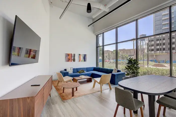 Modern living room with large windows, featuring a flat-screen TV at Post Chicago Apartments.